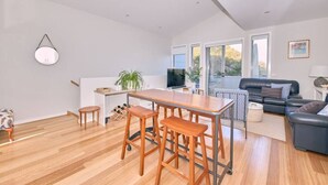 A modern living space with a kitchen area, dining table, and seating. - Grove Hideaway - immaculate 2 bed townhouse (Ocean Grove)