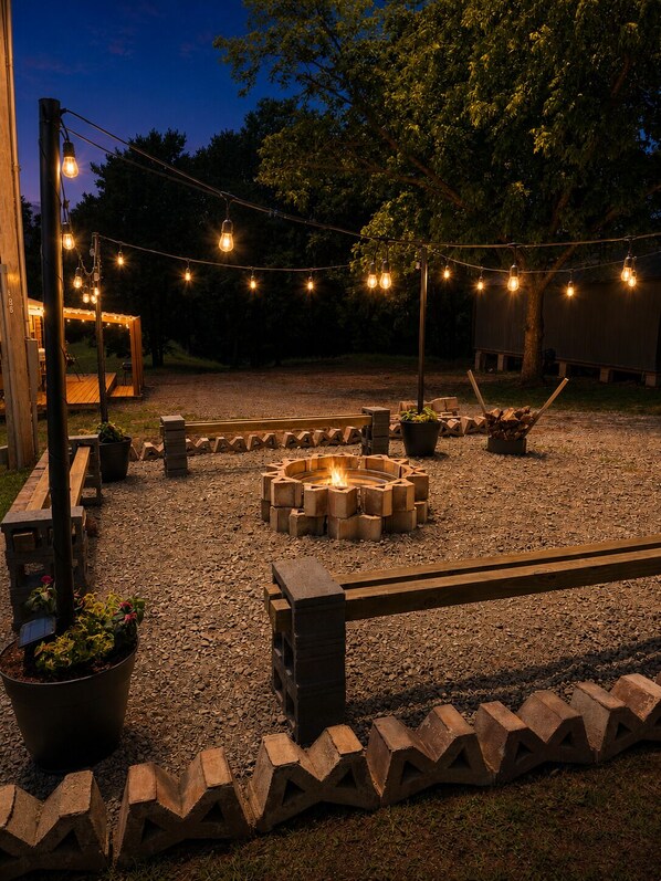 Een terras met een vuurkuil, lichtjes en tuinmeubilair.
