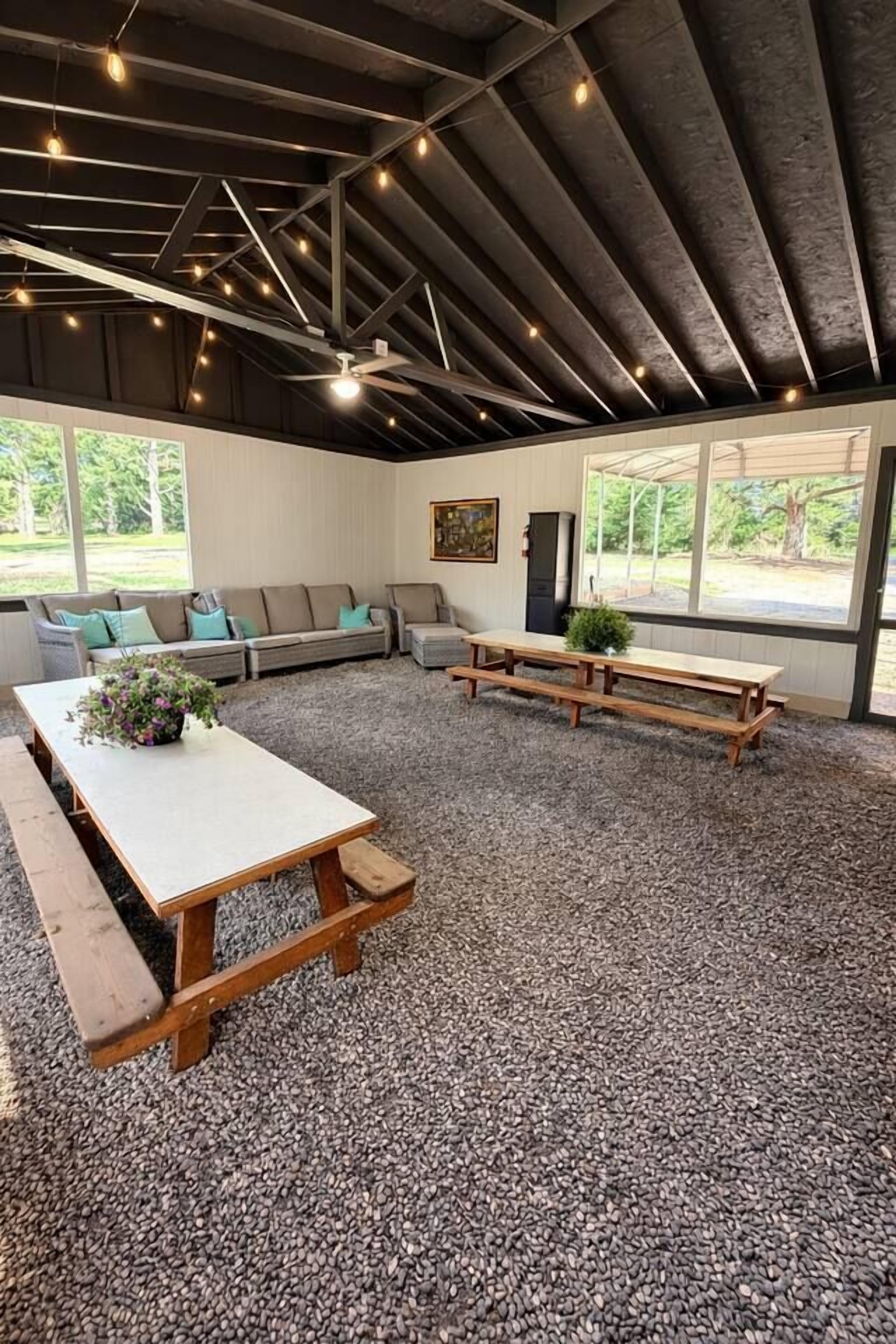 Ein Innenraum mit hoher Decke, Holzbänken, einem Tisch und einer Couch.
