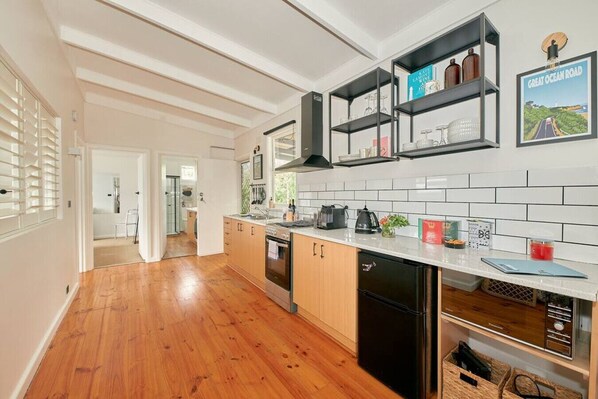 A modern kitchen with wooden cabinets, a black dishwasher, and a white tiled backsplash.