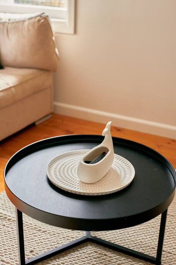 A round black table with a white decorative object on top.