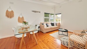 Un salon moderne avec une table à manger en verre, un canapé beige et un plancher en bois.