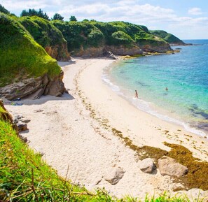 A beach with clear turquoise water, sandy shore, and green hills in the background. - LUXURY - Magnificent 4-bedroom luxury villa by Groom* (Larmor-Plage)