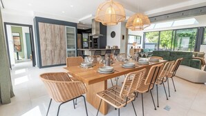Un comedor moderno con una mesa de madera preparada para seis comensales, rodeada de sillas de mimbre.