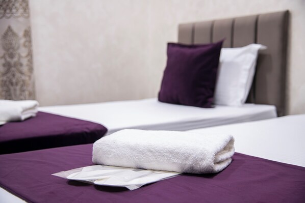 A hotel room with two beds, each with a purple bedspread and white linens. - Art Home Hotel (Tashkent)