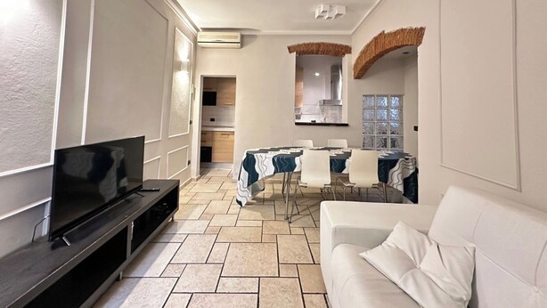 A modern living room with a flat-screen TV, a white sofa, and a dining area with a table and chairs. - Tuscan accommodation (20 minutes from Florence) (Prato)