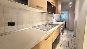 A modern kitchen with white tiles, wooden cabinets, a stainless steel sink, and a gas stove. - Tuscan accommodation (20 minutes from Florence) (Prato)