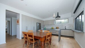 Una cucina moderna con pavimento in legno, un'isola centrale e illuminazione a sospensione.