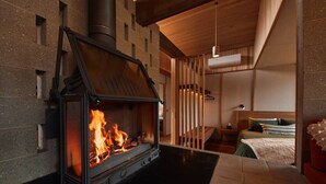A modern interior with a wood-burning stove, a bed, and a hanging light fixture.