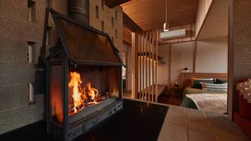 Un intérieur moderne avec un poêle à bois, un lit et un luminaire suspendu.