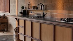 A modern kitchen with a wooden countertop, a built-in stove, and a brick backsplash.
