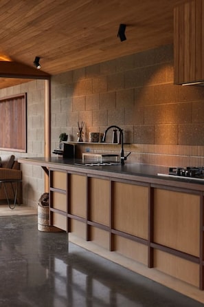 Een moderne keuken met een houten aanrechtblad, een inbouwfornuis en een achterwand van baksteen.