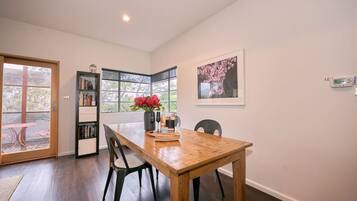 A dining area with a wooden table, chairs, a bookshelf, and a window with a view.