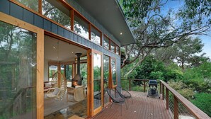 A modern house with large glass windows, a deck, and a fireplace. - Kurraburra Lodge (Anglesea)