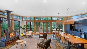 A spacious living area with a fireplace, dining table, and comfortable seating. - Kurraburra Lodge (Anglesea)