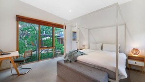 A bedroom with a canopy bed, a desk, and a view of greenery outside. - Kurraburra Lodge (Anglesea)