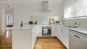 A modern kitchen with white cabinetry, a built-in oven, a microwave, and a dishwasher. - Secluded Anderson - in the heart of Torquay (Torquay)