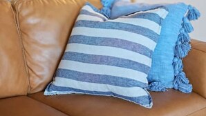 A brown leather sofa with a striped pillow and a blue fringed pillow. - Secluded Anderson - in the heart of Torquay (Torquay)