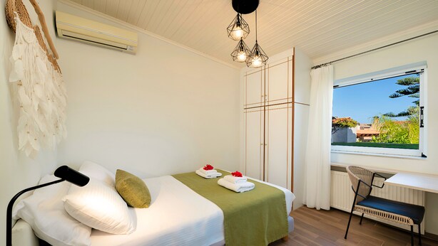 Un dormitorio con cama, escritorio, silla, ventana con vistas y lámpara colgante.