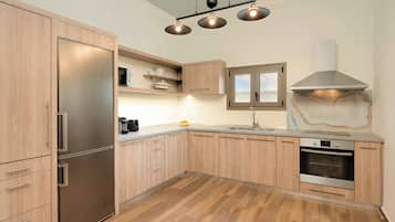 Een moderne keuken met houten kasten, een roestvrijstalen koelkast, een inbouwoven en hanglampen.