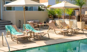 A poolside area with lounge chairs and umbrellas, a small table with drinks, and a view of the pool. - Villa di Capaka Private Pool (Roupes)