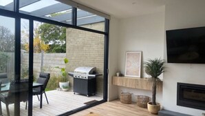 Ein modernes Wohnzimmer mit Glastür zum Außenbereich, einem Kamin und einem Wand-Fernseher.
