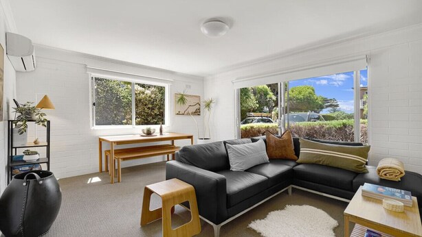 A modern living room with a black leather sofa, a wooden coffee table, a white rug, and a dining area with a wooden table and chairs. - Cosy living at Cosy corner (Torquay)