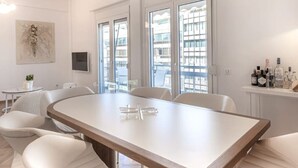 Un espace repas moderne avec une longue table, des chaises blanches et un lustre.