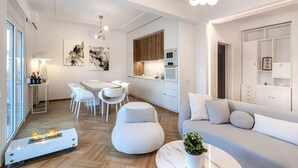 Un salon moderne comprenant un canapé, un coin repas avec des chaises, une cuisine avec des placards et une cheminée.
