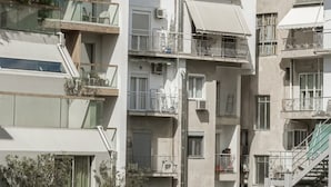 Un immeuble à plusieurs étages doté de balcons, un ciel dégagé et une structure classique en arrière-plan.