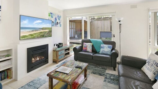 A living room with a fireplace, a sofa, a coffee table, and a television. - Beach Breeze Bungalow - in the heart of Torquay (Torquay)