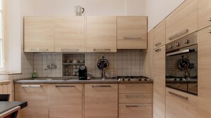 Una cocina moderna con armarios de madera clara, una estufa a gas y una cafetera.