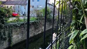 A canal with a house in the background, a red car parked by the canal, and greenery along the canal's edge. - Comfort Studio Apt Near Klosterneuburg (Klosterneuburg)