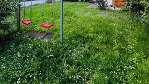 A grassy area with a swing set, a small shed, and a building with multiple windows and a staircase. - Comfort Studio Apt Near Klosterneuburg (Klosterneuburg)