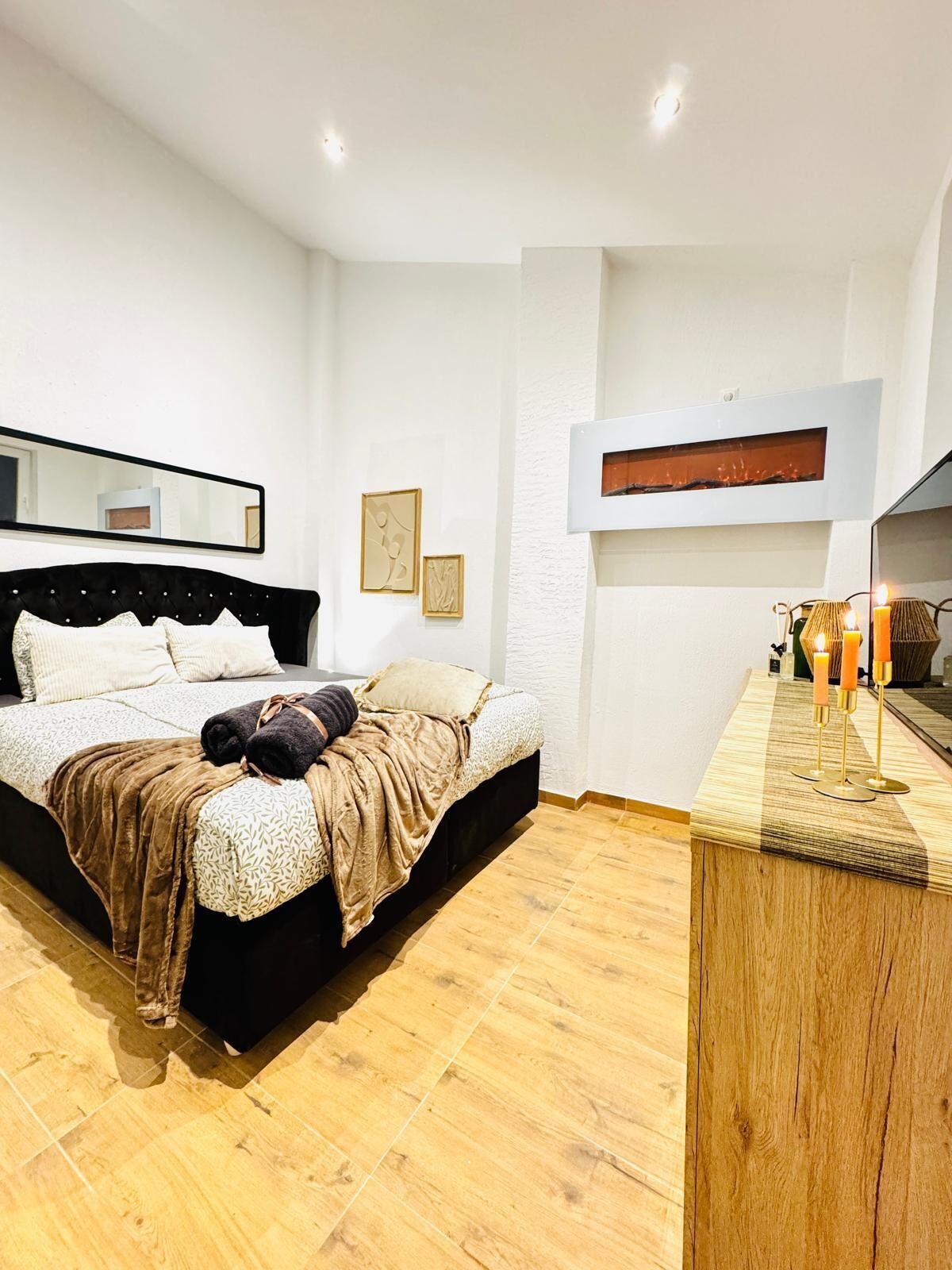 Une chambre à coucher moderne avec un grand lit, une armoire en bois et un miroir au mur.