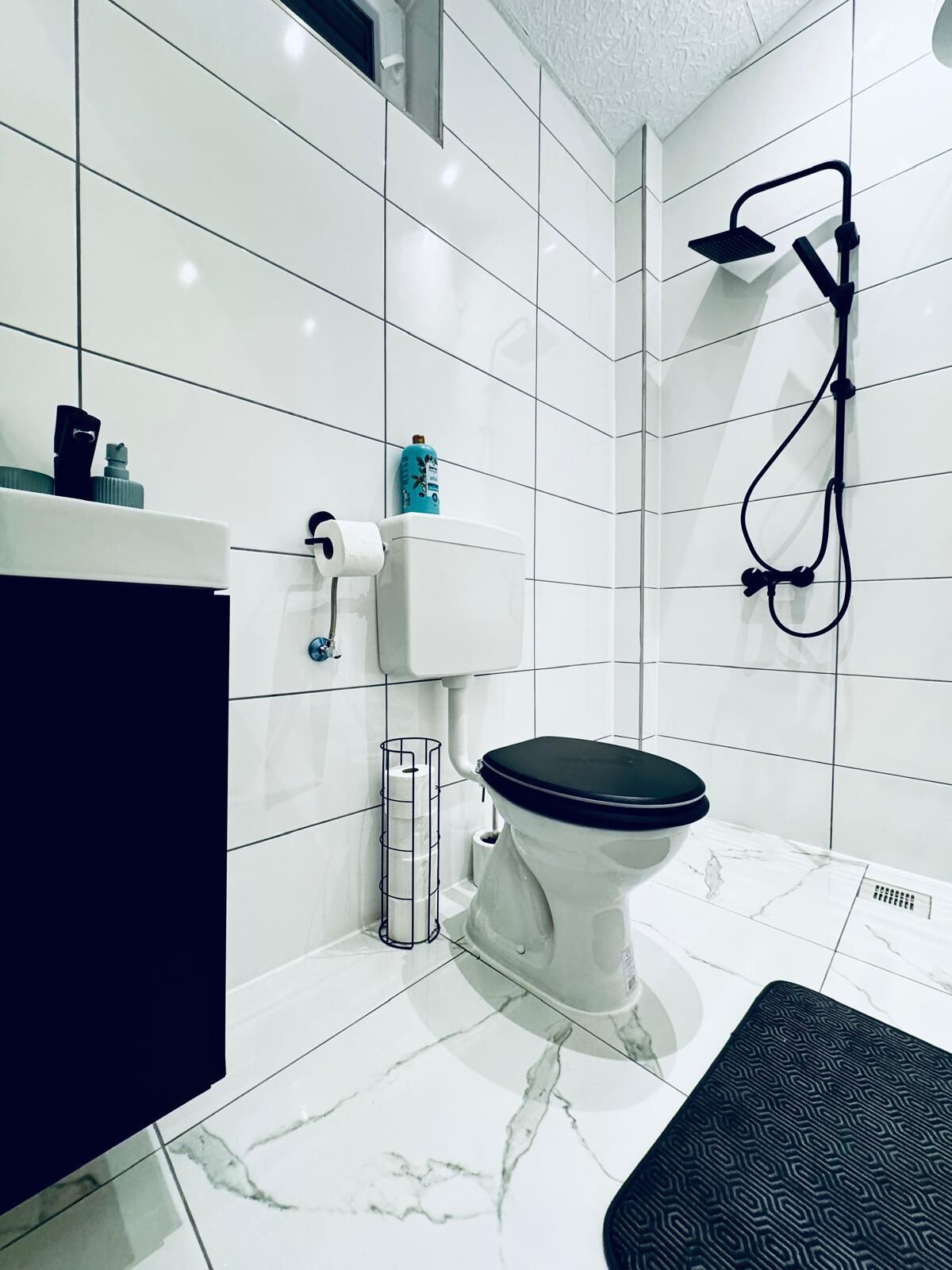 A modern bathroom with a toilet, a shower, and a marble floor.