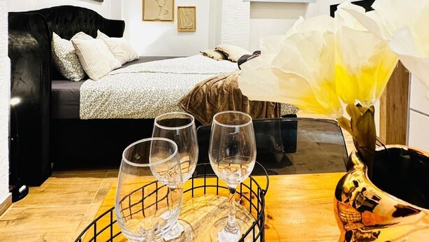 A bedroom with a bed, a bedside table with wine glasses, a vase with flowers, and a fireplace. - Comfort Studio Apt Near Klosterneuburg (Klosterneuburg)