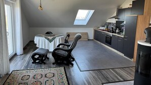 Une cuisine moderne avec des meubles de couleur sombre, une cuisinière noire et une lucarne au-dessus de l’espace repas.