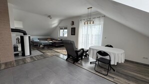 Un loft spacieux avec un plafond haut, un coin repas comprenant une table et des chaises, un canapé et une grande fenêtre avec des rideaux.