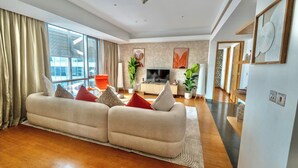 A modern living room with a large sofa, a flat-screen TV, and a dining area. - Premium Vacation Home in Old Dubai  (Dubai)