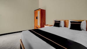 Une chambre d’hôtel avec un grand lit, une armoire en bois et une table de chevet.
