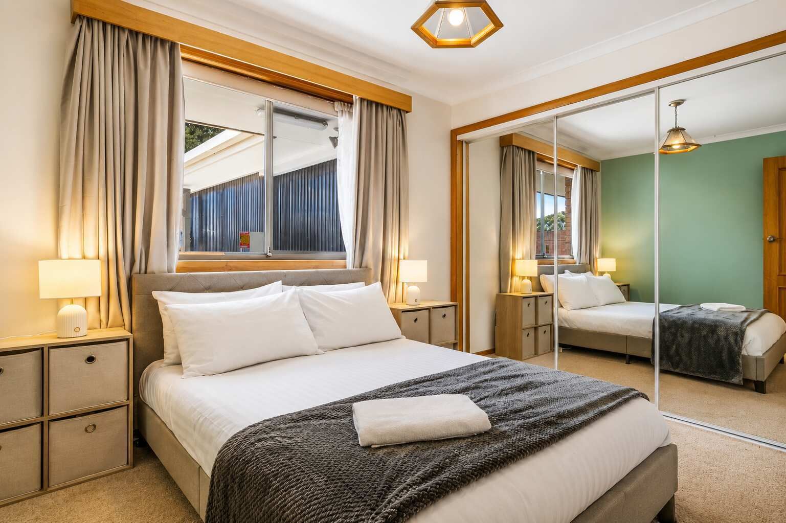 Ein Hotelzimmer mit einem Bett, Nachttischen, einem Spiegel und Blick ins Freie.