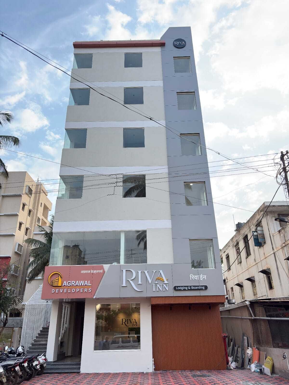 A multi-story building with a Riva Inn sign, featuring a modern design with large windows and a flat roof.