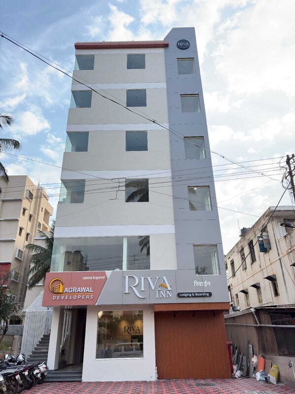 A multi-story building with a Riva Inn sign, featuring a modern design with large windows and a flat roof.