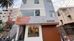 A multi-story building with a Riva Inn sign, a visible staircase, and a parking area with motorcycles. - HOTEL RIVA INN (Miraj)