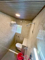 Un baño pequeño y moderno con ducha, inodoro y bañera con mampara de vidrio.