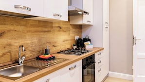 A modern kitchen with a wooden backsplash, stainless steel sink, and white cabinets. - Dimora del Lario (Como)