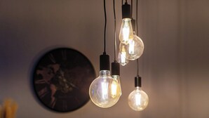 A wall with three hanging light bulbs and a clock. - Dimora del Lario (Como)