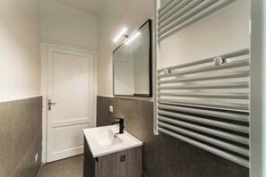 Une salle de bain avec un lavabo blanc, un miroir et un porte-serviettes.