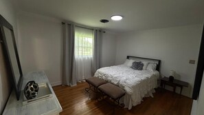 Un dormitorio con cama, un banco, una mesita de noche y un espejo.